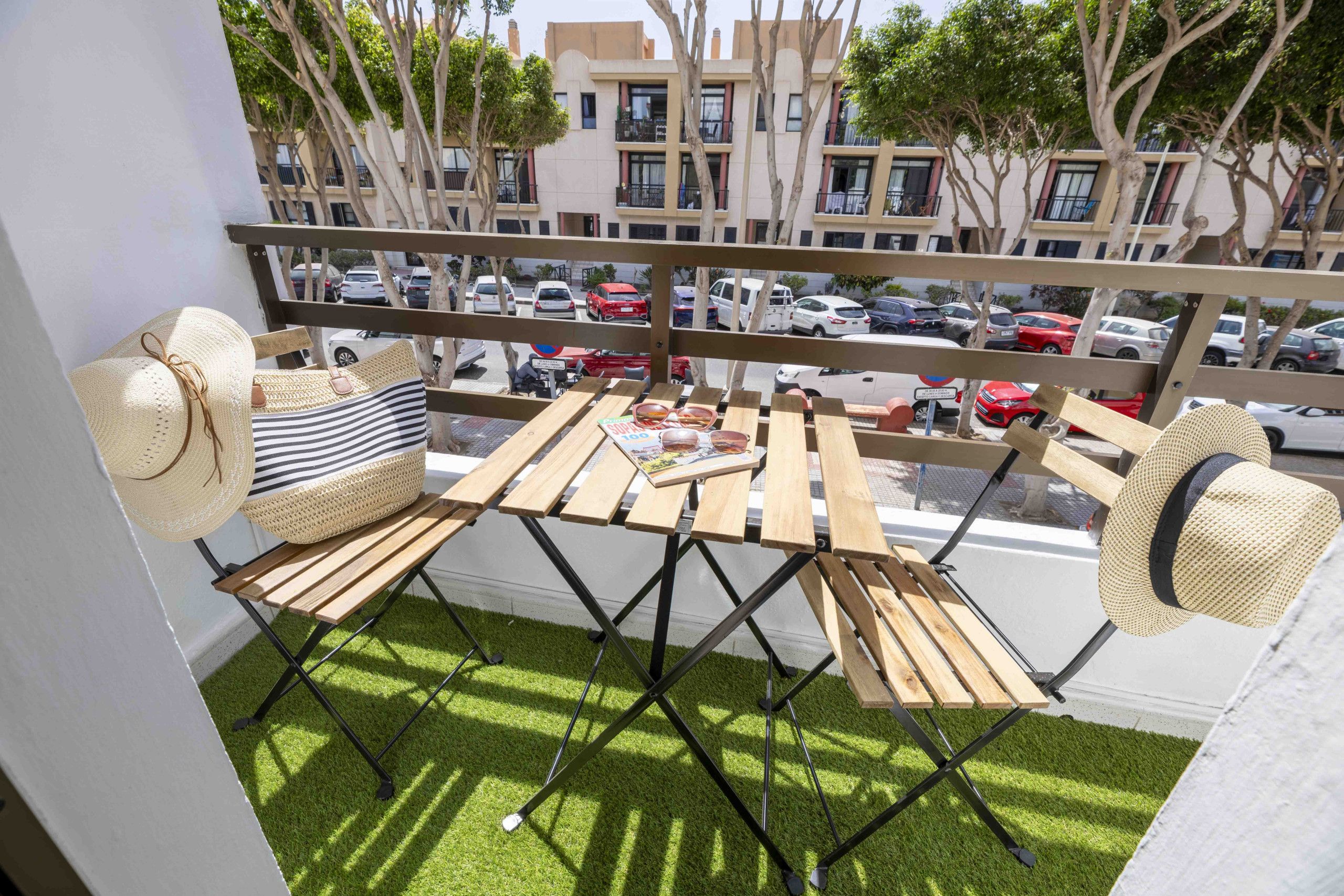 Un balcon avec une table et des chaises, un chapeau et un magazine.