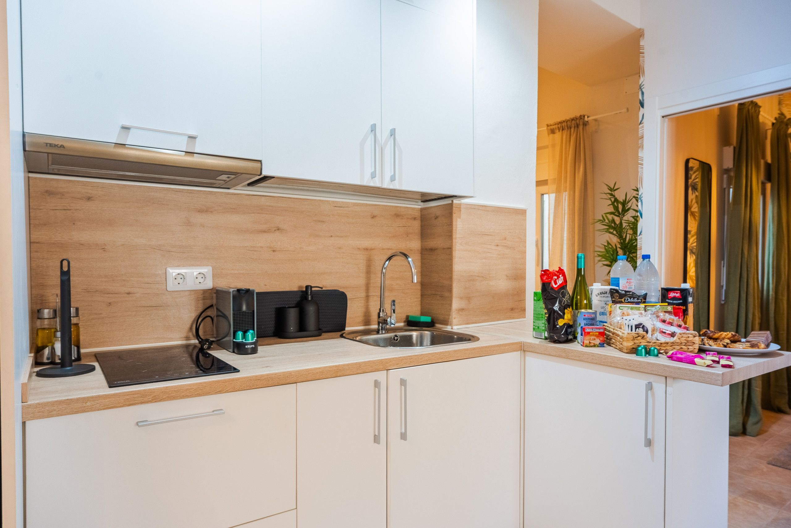Une cuisine moderne avec des armoires blanches, un évier en acier inoxydable et un pare-feu en bois.
