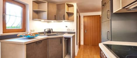 A compact kitchen with built-in appliances, a window, and a door leading to another room.