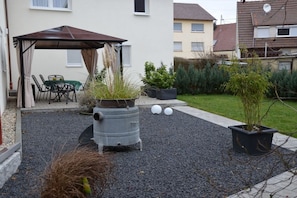 A patio area with a covered seating area, a large metal pot, and potted plants. - Holiday home in Hülben with swimming pool (Hülben)