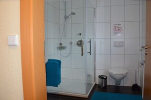 A bathroom with a glass-enclosed shower, a toilet, and a trash bin. - Holiday home in Hülben with swimming pool (Hülben)