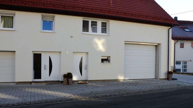 Ett tvåvåningshus med ett garage, en uppfart och en liten trädgård.