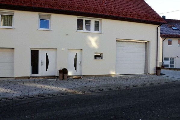 A two-story house with a garage, a driveway, and a small garden area. - Holiday home in Hülben with swimming pool (Hülben)