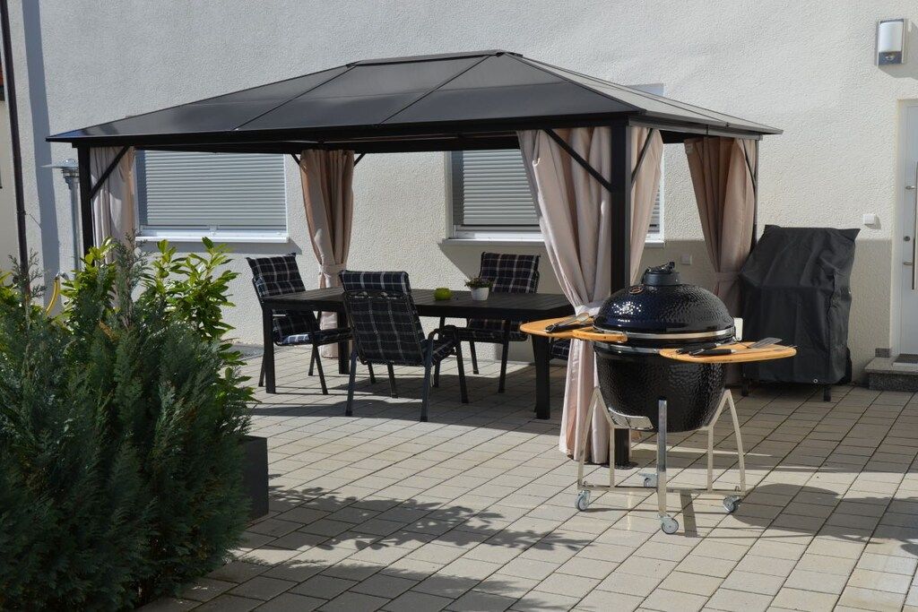An outdoor patio with a table and chairs, a grill, and a covered seating area.