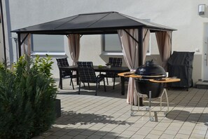 An outdoor patio with a table and chairs, a grill, and a covered seating area. - Holiday home in Hülben with swimming pool (Hülben)