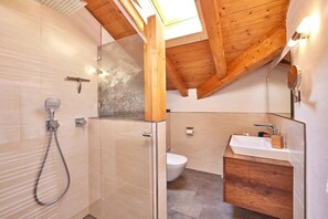 A modern bathroom with a shower, toilet, and vanity. - Alpklang Apartment #2 (Garmisch-Partenkirchen)