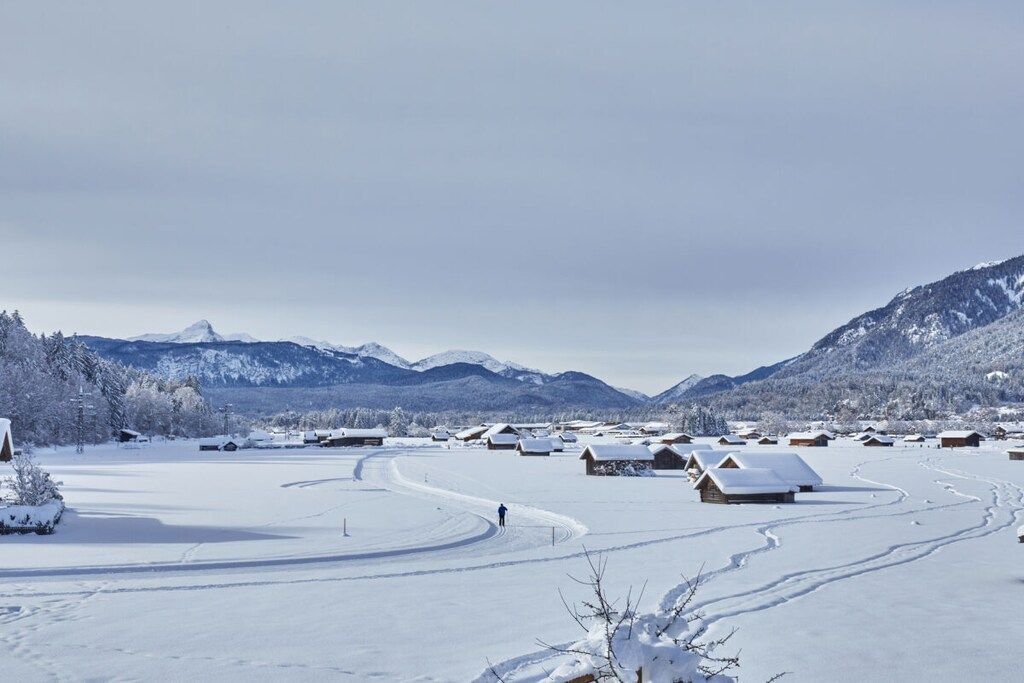Un paysage enneigé, avec des chalets en bois et un ciel dégagé.
