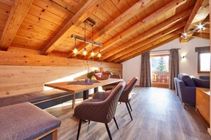 A wooden interior with a dining area, seating, and a view through a window. - Alpklang Apartment #2 (Garmisch-Partenkirchen)