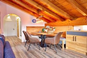 A wooden interior with a dining table, chairs, and a kitchen area. - Alpklang Apartment #2 (Garmisch-Partenkirchen)