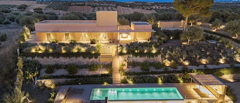A modern villa with a swimming pool, outdoor seating, and landscaped gardens.