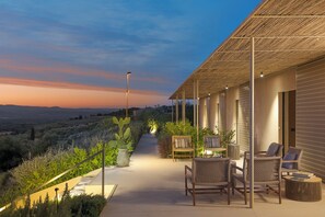 Eine Terrasse mit Korbmöbeln und Blick auf die Landschaft bei Einbruch der Dunkelheit.