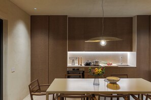 Une cuisine moderne dotée d’un îlot central, d’une table à manger avec des chaises et d’un luminaire suspendu.