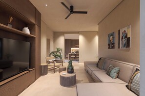 Ein modernes Wohnzimmer mit Fernseher, Deckenventilator, Sofa, Couchtisch und Essbereich im Hintergrund.