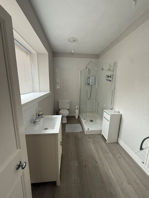 Une salle de bain équipée d’une douche, de toilettes, d’un lavabo et d’un meuble de rangement.
