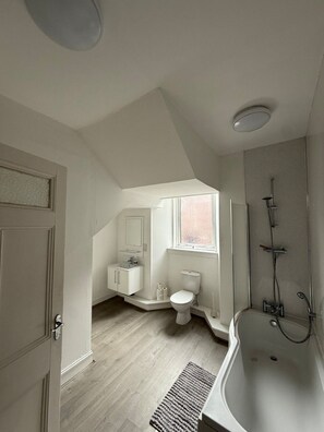 A modern bathroom with a freestanding bathtub, a shower area, and a toilet. - Spacious 3 Bedroom Apartment (Kirriemuir)