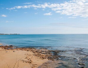Ein Strand mit blauem Himmel und ruhigem Wasser.