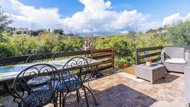 An outdoor patio with a table and chairs, a bench, and a wicker sofa. - Charming Villa with Lemon Garden Near Lido di Noto Beach (Noto)