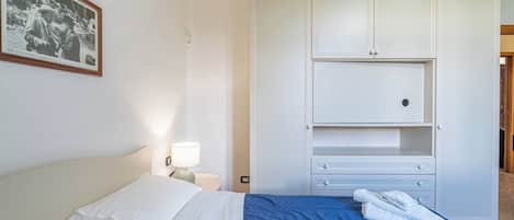 Un dormitorio con una cama, una mesita de noche, una lámpara, un armario y un cuadro en la pared.