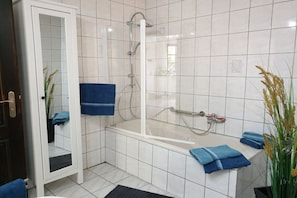 A bathroom with a glass-enclosed shower, a bathtub, and a mirror with a door. - Dream view of the Rursee (Simmerath-Woffelsbach)