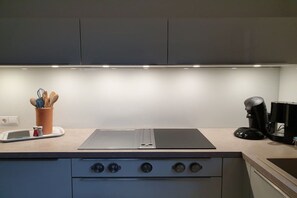 A kitchen with a built-in stove, a coffee maker, and a utensil holder on the countertop. - Dream view of the Rursee (Simmerath-Woffelsbach)