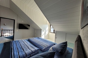 A bedroom with a bed, pillows, a TV, and a window. - Dream view of the Rursee (Simmerath-Woffelsbach)