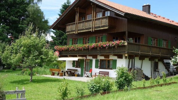 A two-story wooden house with a balcony, a covered patio, and a staircase leading to the upper floor. - Holiday home with 3 bedrooms (Weitnau-Hellengerst)