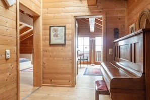 Un interior de madera con un banco, un cartel enmarcado y una puerta que da a otra habitación.