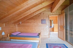 A wooden cabin with a loft bedroom, a bed with checkered bedding, and a visible bathroom. - Holiday home with 3 bedrooms (Weitnau-Hellengerst)