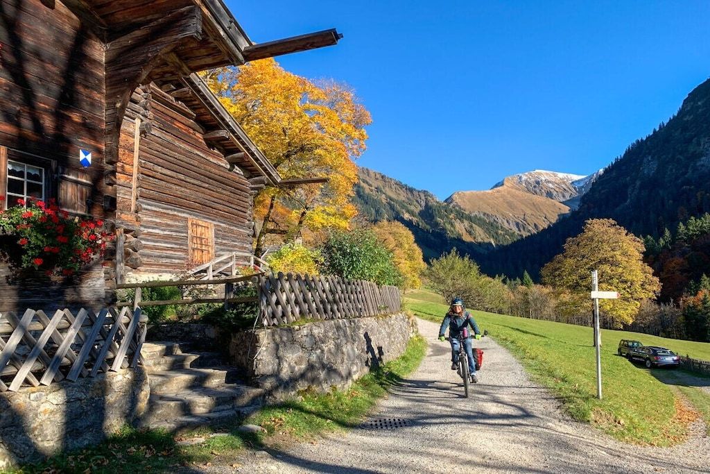 A rustic wooden building with a stone wall and a wooden fence.