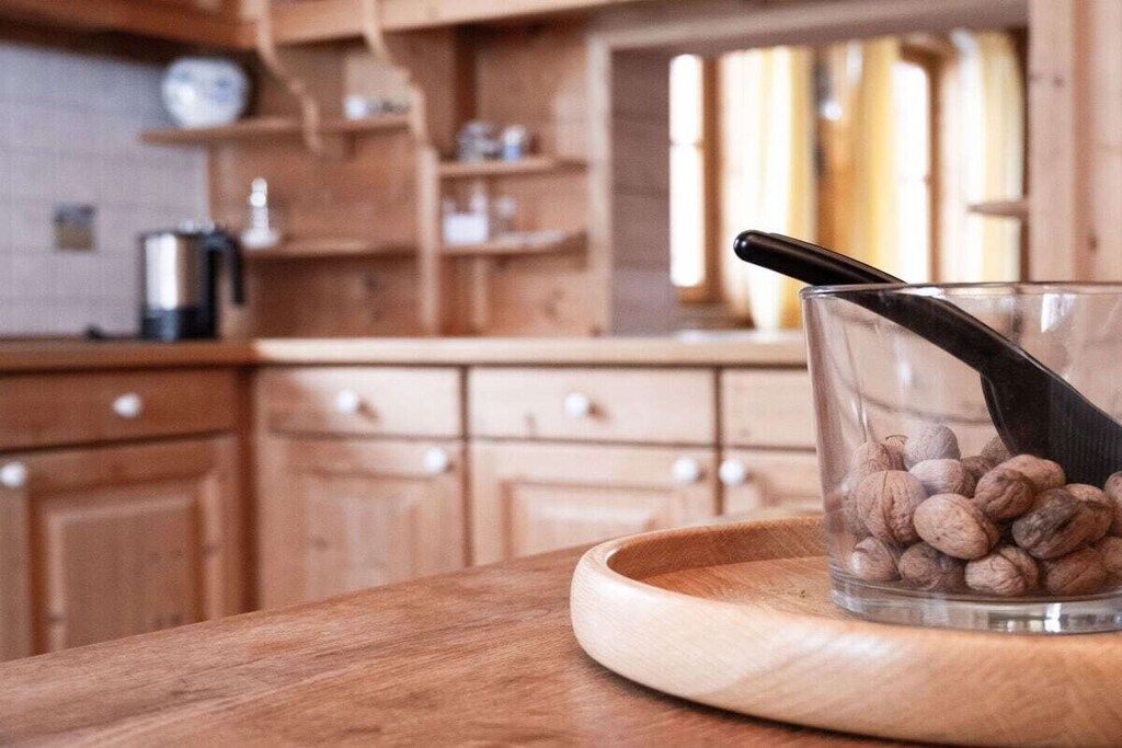 A kitchen with wooden cabinets, a coffee maker, and a glass container with coffee beans on a wooden tray.