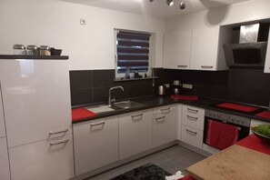 A modern kitchen with white cabinets, a black countertop, and a red towel. - Holiday apartment with 3 bedrooms (Bacharach- Henschhausen)