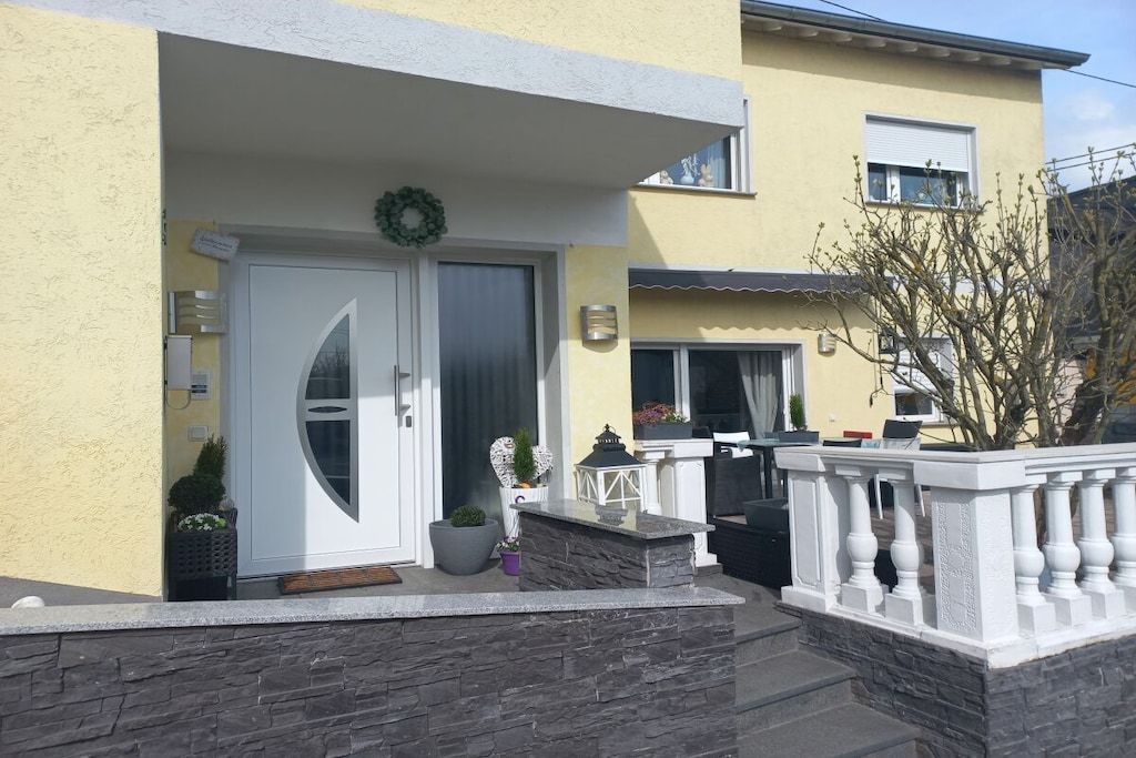 Un bâtiment avec une porte blanche, un mur en pierre et un balcon doté d’une balustrade.