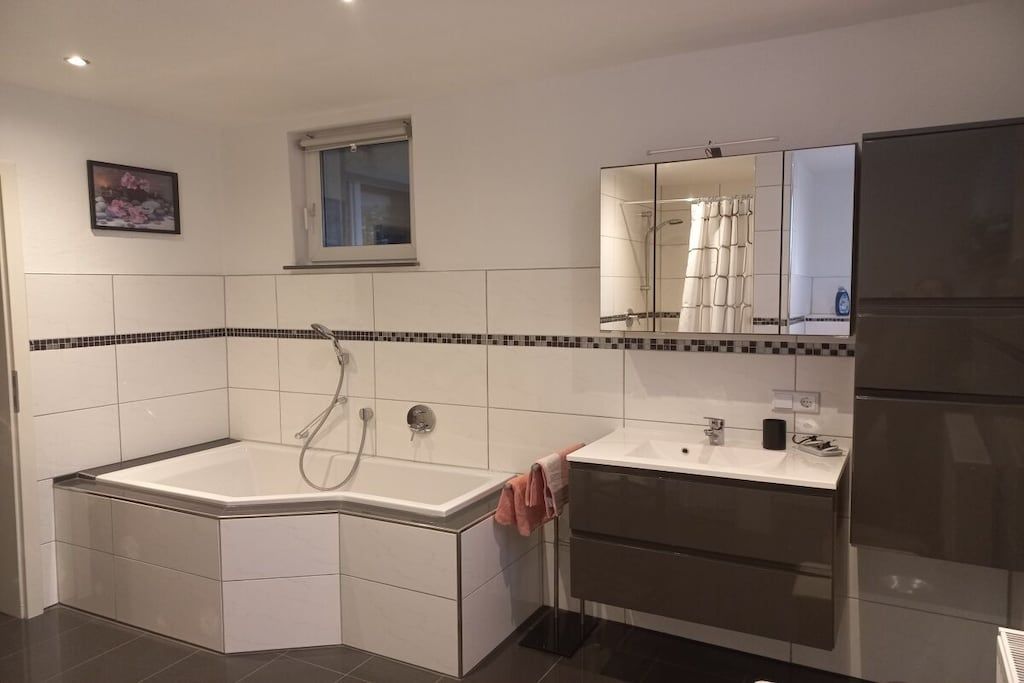 A modern bathroom with a freestanding bathtub, a vanity with a mirror, and a shower area.