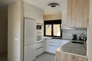 A modern kitchen with a built-in oven, microwave, and sink. - Apartment Tortuguero (Morro Jable, Jandia, Fuerteventura)