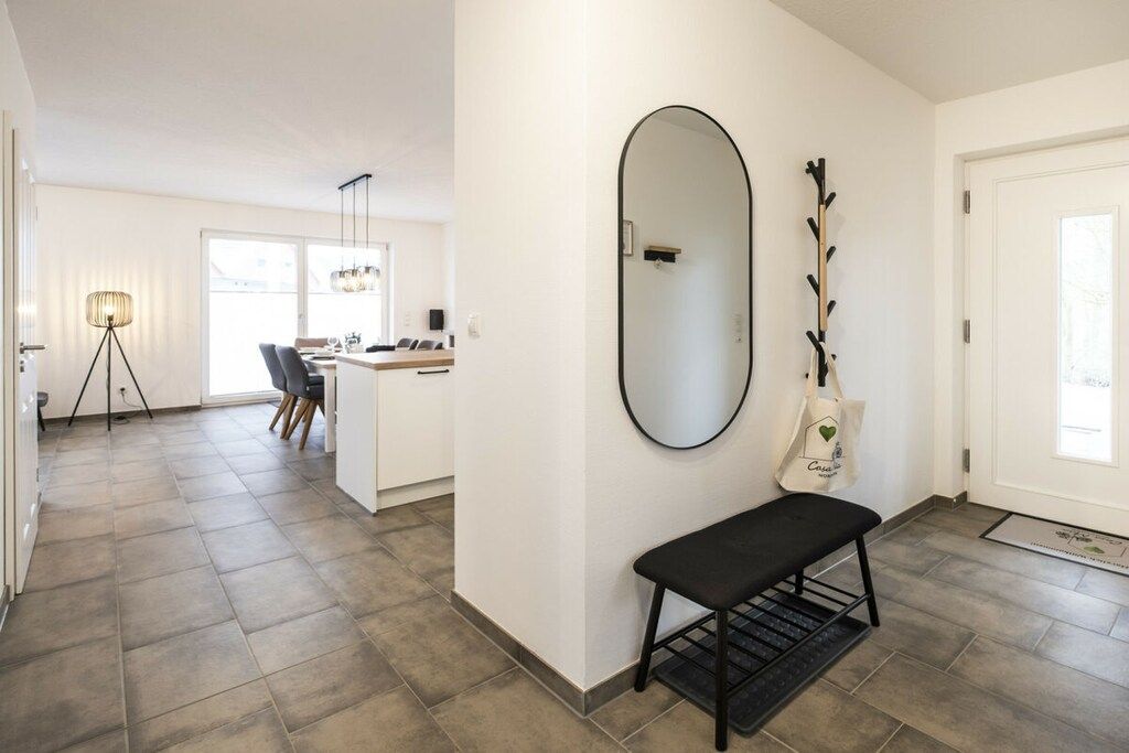 A modern interior with a bench, a mirror, and a coat rack.