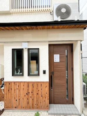 A building with a wooden facade, a brown door, and a small window. - Ichizuru House Tsuruhashi OSAKA (Osaka)