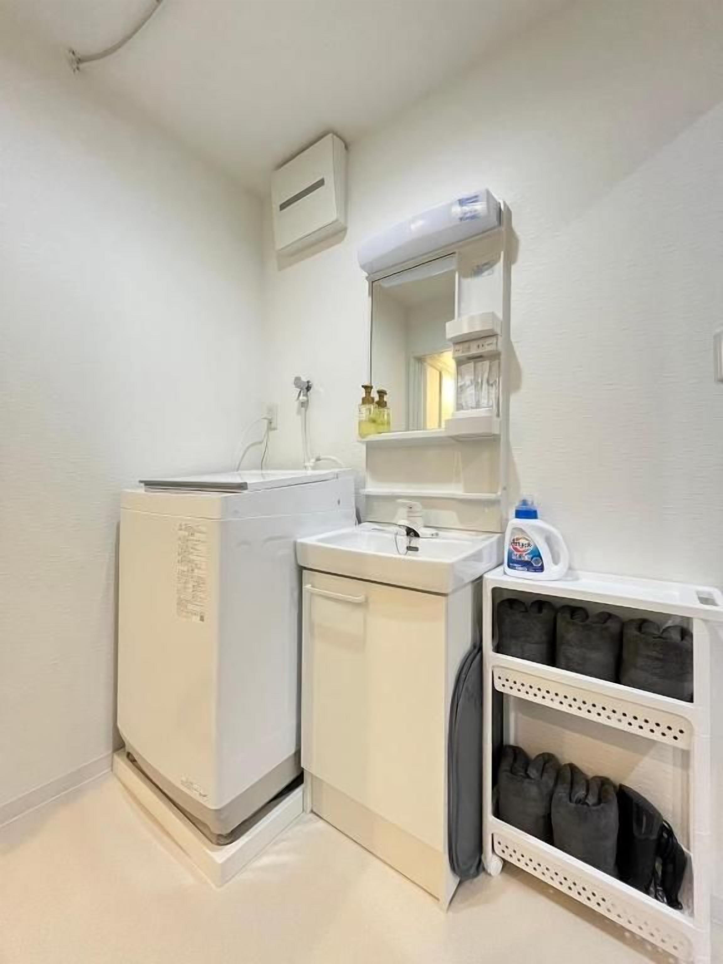 A compact laundry room with a washing machine, a dryer, a sink, and a shelf with cleaning supplies.