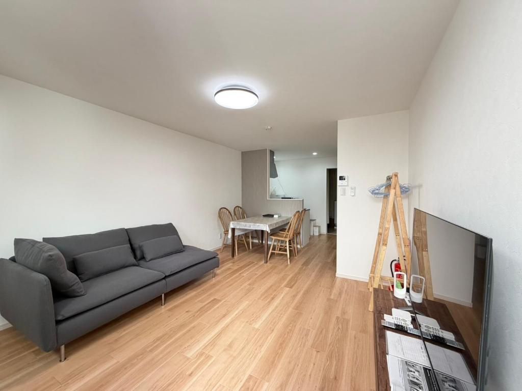 A modern living room with a sofa, dining table, and a TV on a stand.