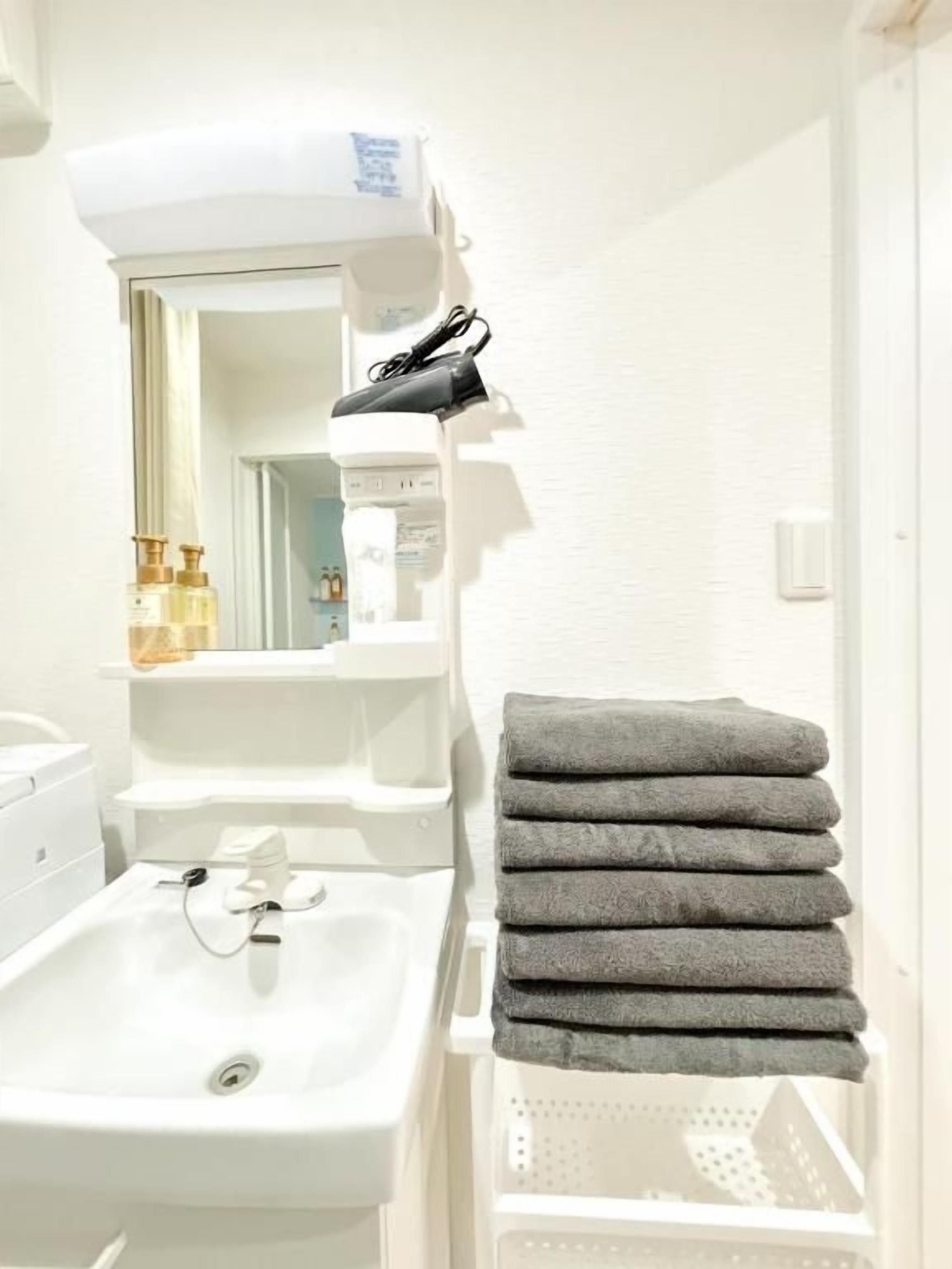 A bathroom with a sink, mirror, towel rack, and a white wall.