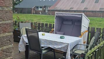 A patio with a table and chairs, a covered seating area, and a brick wall.
