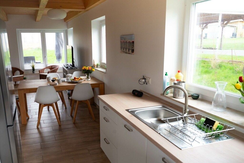 Una cocina moderna con encimera de madera, armarios blancos, un lavaplatos integrado y una ventana con vistas a un jardín.