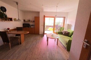 Un espacio habitable compacto con comedor, sofá y vista a una terraza.
