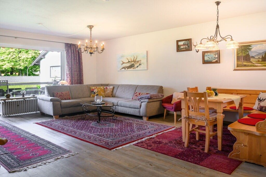 Uma sala de estar com sofá, mesa de centro e um espaço de jantar com mesa e cadeiras.