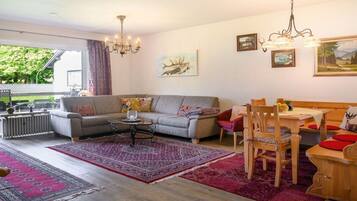 Een woonkamer met een bank, salontafel en een eethoek met tafel en stoelen.