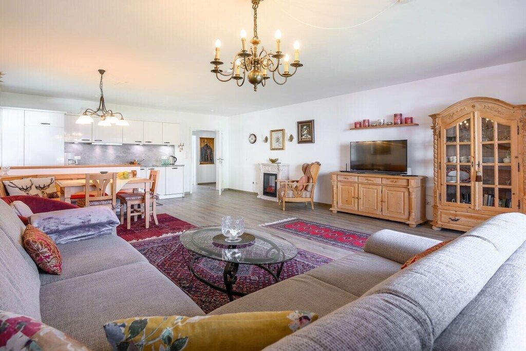 Ein Wohnzimmer mit einer Couch, einem Glastisch, einer Deckenleuchte, einem Fernseher und einem Schrank.