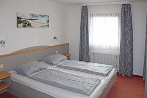 A hotel room with two beds, a window with curtains, a radiator, and a wall-mounted picture. - Holiday home Aggenstein (Lechbruck)