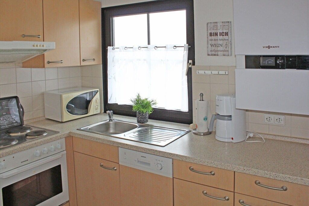A kitchen with a stove, microwave, sink, and coffee maker.