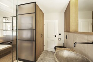 Ein modernes Badezimmer mit Duschkabine aus Glas, einer freistehenden Badewanne und einem großen Spiegel über dem Waschbecken.