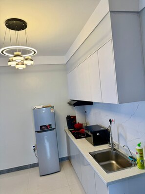 A modern kitchen with white cabinets, a stainless steel sink, and a built-in oven. - Charming apartment in Pridelands with access to fitness room (Pridelands)