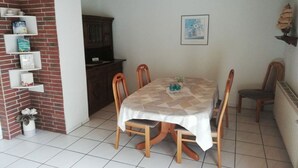 A dining area with a table set for four, surrounded by wooden chairs. - Holiday home in Fehmarn with swimming pool (Fehmarn)